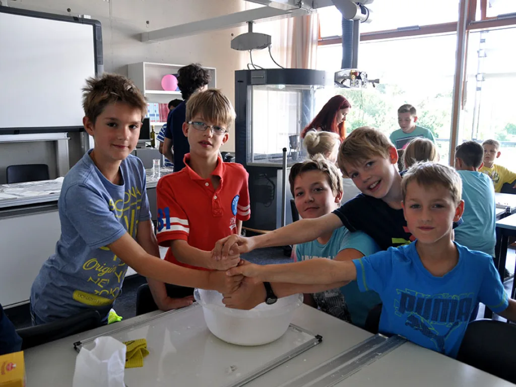 Kinder rühren gemeinsam in einer Schüssel.